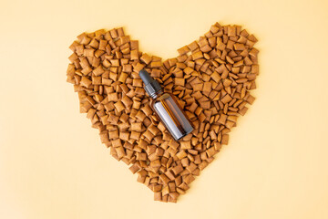 Mineral and vitamin tincture or homeopathic medical treatment for cats and dogs in brown vial with pipette. Natural supplements for pets. Mockup of bottle on heart-shaped pet's food. Flat lay