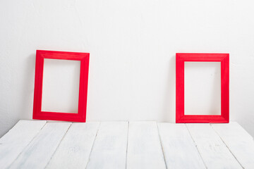 pair of empty red picture frames on white wooden table