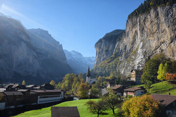 Fototapeta na wymiar Lauterbrunnen village with Staubbach waterfall and in Berner Oberland, Switzerland. Scenic alpine view over a valley with a famous church. Popular tourist attraction.
