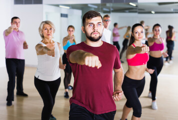 vigorous people of different ages posing in fitness studio