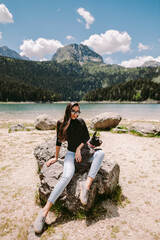 Fototapeta premium woman relax in mountains and holding cute dog . Female tourist relax in mountains with cute pet. Traveling with pet.