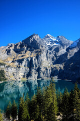 Fototapeta na wymiar Oeschinensee lake in Kandersteg, Switzerland. Panoramic view of the mountains and azure water on a clear sunny summer day. Popular tourist attraction.