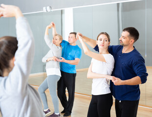Fototapeta premium Group of happy adult people dancing modern social dances in pair at .dance school