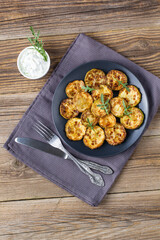 Fried slices of zucchini with sour cream sauce. Courgettes with herb for dinner on natural wooden background