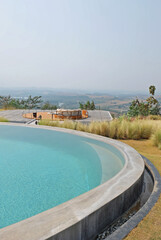 Exterior architecture and decoration of swimming pool design with green mountain view and cloudy blue sky