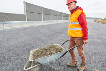 Construction worker with wheelbarrow full of concrete on construction site