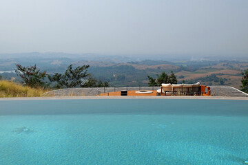 Exterior architecture and decoration of swimming pool design with green mountain view and cloudy blue sky