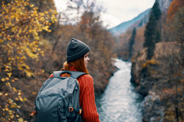 woman hiker with backpack on her back near mountain river in nature