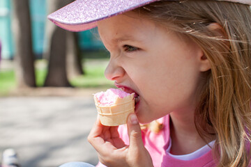 Little happy girl walking in the park in summer and eating ice cream. High quality photo