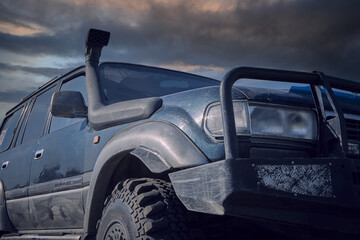 4x4 SUV with a snorkel on the background of a stormy sky. The concept of extreme travel. © Aleksandr