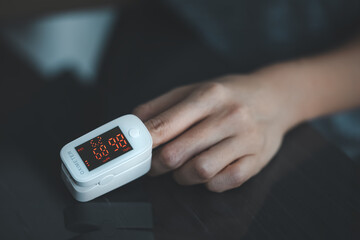 closeup woman hand self monitoring on pulse oximeter