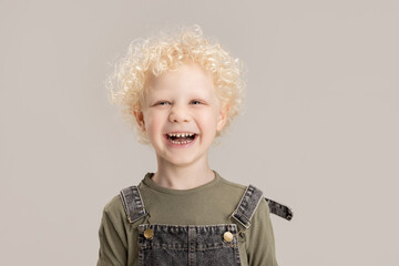 Portrait of little preschool boy posing isolated over gray studio background.