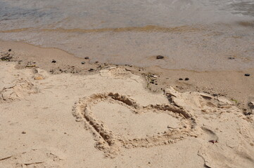 Das Liebesgeständnis: ein Herz auf dem Sandstrand nahe am Wasser
