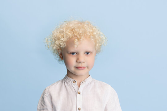 Portrait of preschool boy posing isolated over blue studio background.