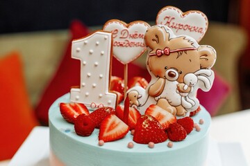 A beautiful birthday cake for a children's birthday. Gift for a girl for 1 year. Decorations on the cake with strawberries and cartoon characters, hearts. The inscription - Happy Birthday Kirochka.