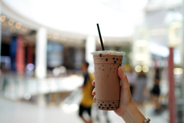 Iced Chocolate - Hand holding plastic glass of chocolate milkshake with black sugar syrup and hot...
