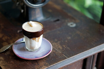 Dirty Coffee - Chocolate rimmed glass of espresso shot mixed with cold fresh milk on blurred background .