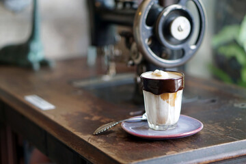 Dirty Coffee - Chocolate rimmed glass of espresso shot mixed with cold fresh milk on blurred background .