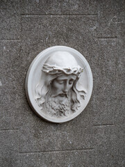 The image of the head of Jesus Christ on a concrete headstone in a cemetery