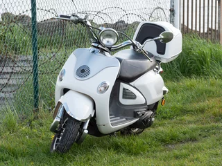 Tuinposter White vintage scooter is parked in the grass © Farantsa