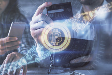 Double exposure of man and woman on-line shopping holding a credit card and crypto theme hologram...