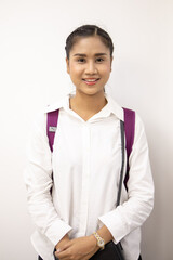 Portrait shot of Asian young happy beautiful long black pigtail hair female model wears white long sleeves shirt and carry purple backpack with golden wrist watch stand smiling hold hands together