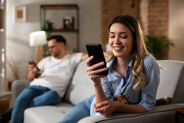 Happy young woman using the phone at home. Excited woman enjoying in the living room.