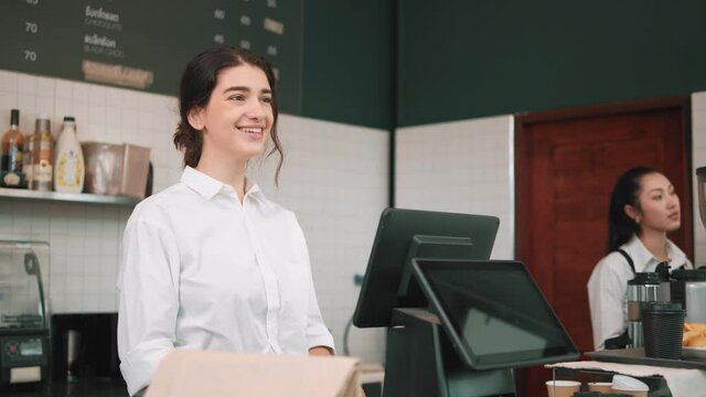 Happy woman barista using touch screen cashier an order and talking to customer at coffee shop. coffee shop Cafe cashier. Business service.