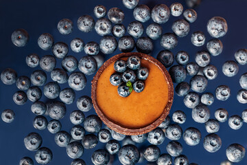 chocolate caramel tartlet with blueberries  in above view on the blueberrie background,  levitation