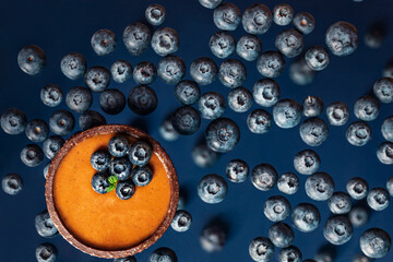 chocolate caramel tartlet with blueberries  in above view on the blueberrie background,  levitation