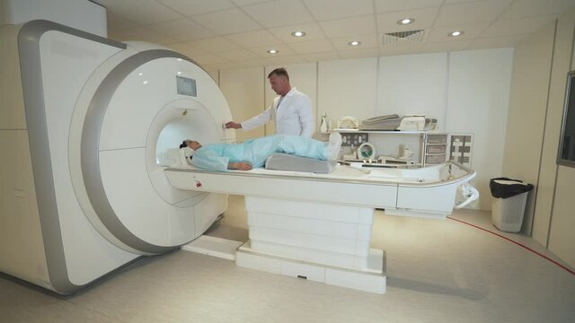 Magnetic resonance imaging, adult professional doctor performs a magnetic tomographic examination of a young asian woman, MRI, modern technologies in medicine, end of the procedure.