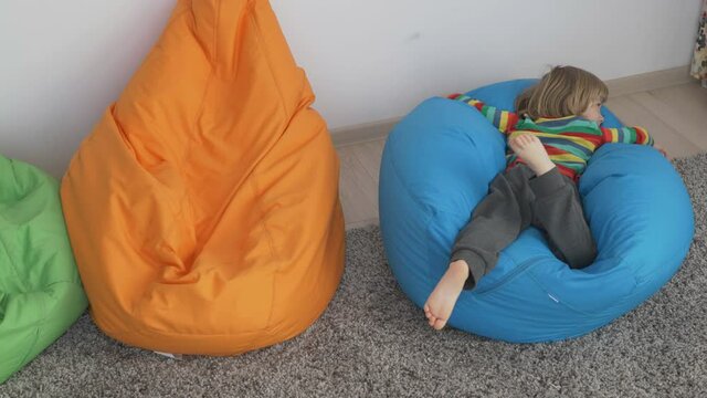 Blond child lying on his belly on a large colorful pillow