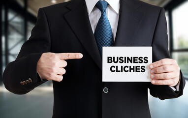 Businessman shows a card with the message business cliches.