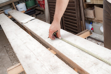 Male carpenter working with wood material in a garage.