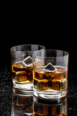 Whiskey with steel cooling cubes on dark glass background