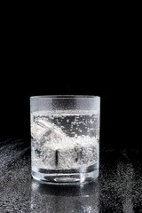 Glass of Soda or Coctail with steel cooling cubes on dark glass background