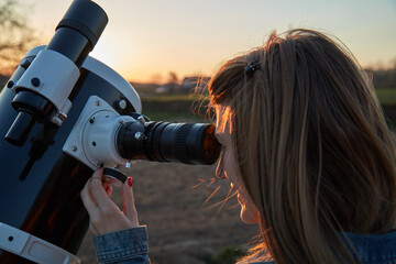 Woman looking at night sky with amateur astronomical telescope.