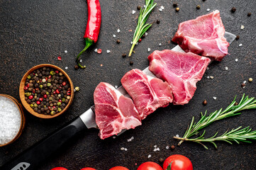 raw T-bone steak on a knife on a stone background