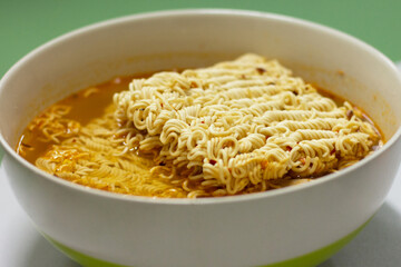 Instant noodles (spicy)  in a bowl, fast food, high sodium.