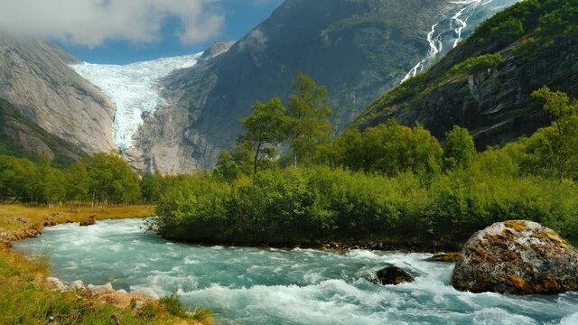 Amazing nature of Norway - Clear water in a mountain stream against the background of a glacier in the mountains.