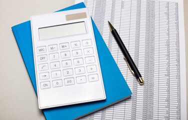 On a light gray table are reports, a blue notebook, a pen, and a white calculator. Business concept