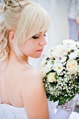 Obraz premium A blonde bride with flowers stands with her back to the viewer