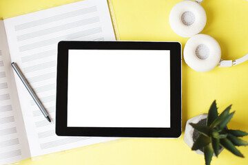 Top view open music book, headphones and a pen on a yellow background. mock up for music lessons