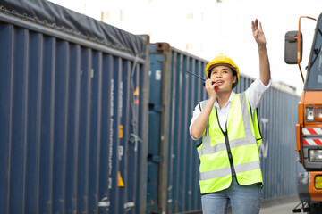 woman factory worker or engineer using walkie talkie and calling someone for preparing a job in containers warehouse storage