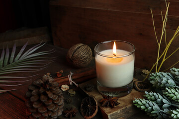 the burning luxury aromatic scented candle glass on the wooden table with background of vintage...