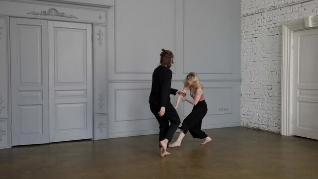 emotional contemporary dance of young woman and man in rehearsal hall