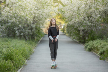 A girl stands on a skateboard with her long hair flying in the sun.Spring Concep