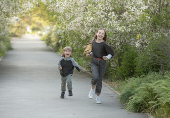 a girl and a boy run along the road. The concept of a brother-sister relationship. Spring background