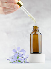 A woman's hand holds a pipette with serum and drips into a bottle. Natural skin care concept. Essential oil with cherry tree extract. Natural herbal products.