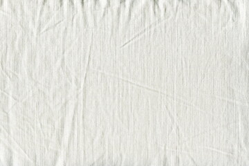 The texture of a simple rough crumpled natural fabric in beige color.  Burlap, background of simple rustic fabric.